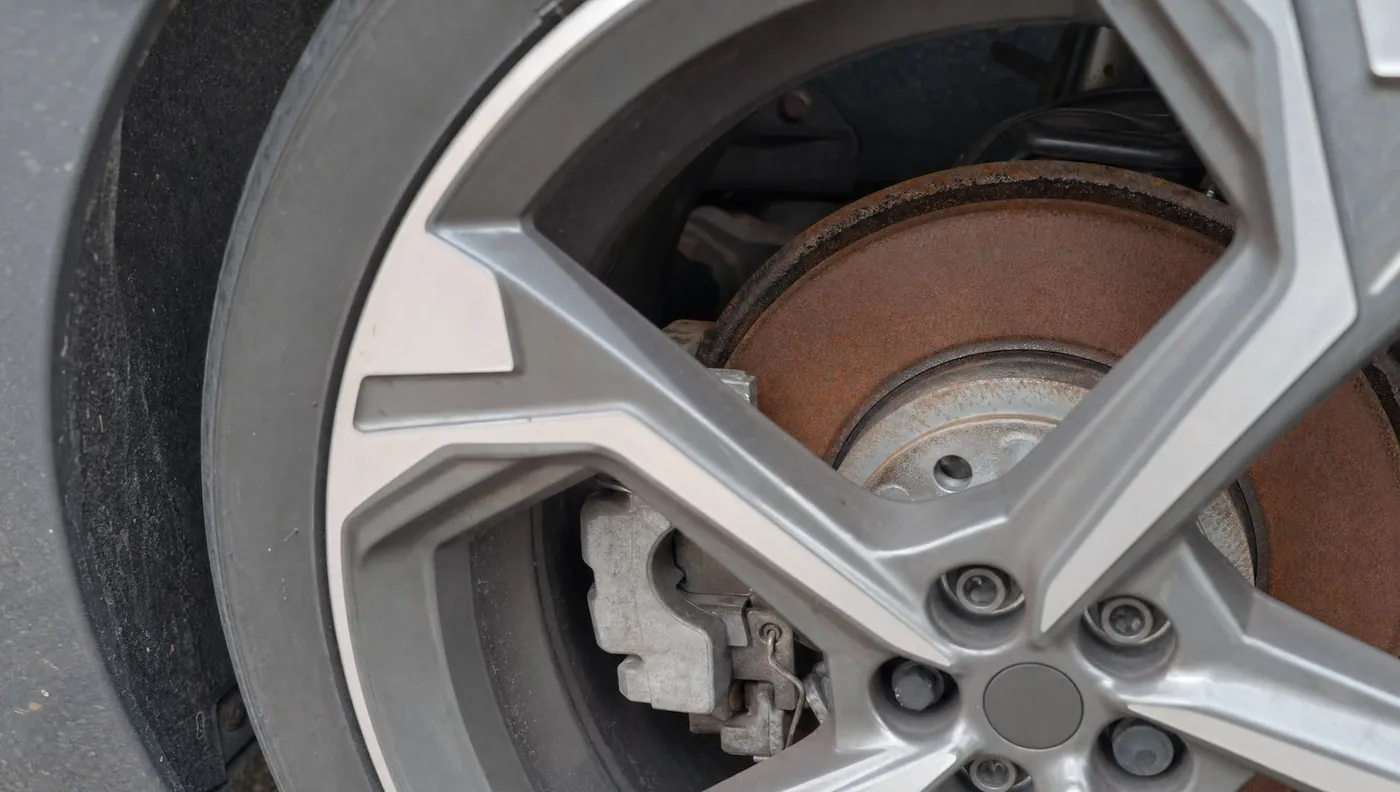 Rostige Bremsscheibe hinter der Felge eines Elektroautos